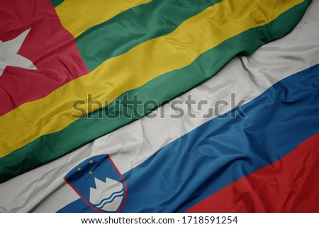 waving colorful flag of slovenia and national flag of togo. macro