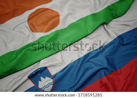waving colorful flag of slovenia and national flag of niger. macro