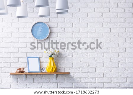 Scandinavian-style room with wooden shelves, decor, children's plane, photo frame and yellow flower daffodil vase. Wall of white decorative brick block. Space for text.
