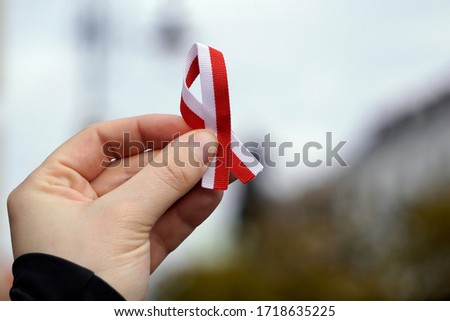 hand with red and white ribbon on background. Flag background national holiday country november celebration.1 of May, November 11, flag or independence or labor day. Government holiday in Royalty-Free Stock Photo #1718635225