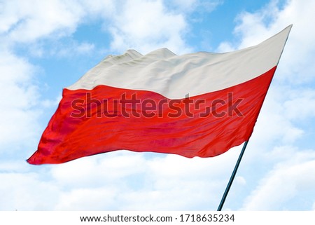 Polish red and white flag against a blue sky, state flag day on may 2 on a Sunny day. May 2, November 11, flag, independence or labor Day. Royalty-Free Stock Photo #1718635234