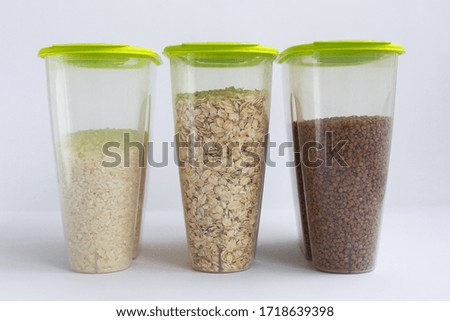 various groats in containers or jars on a white background. Rice, oatmeal and buckwheat