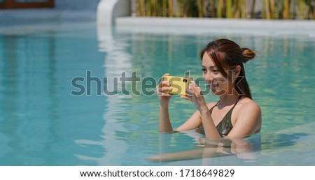 Woman take photo on cellphone in swimming pool
