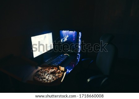 Gamer place at home at night. Gaming chair near a desk with a computer, keyboard, monitor and pizza box for delivery. Gaming concept. Background. Gamer and fast food. Copy space
