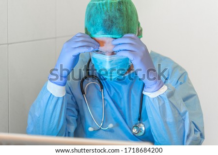 Doctor with uniform cap and mask in his office, showing great concern for the problems that are plaguing the world these days with the COVID-19 virus or Coronavirus.
