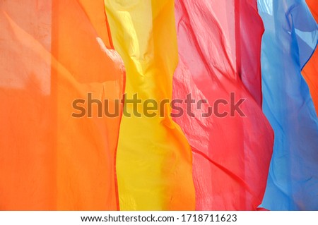 Bright multicolored vertical flags fly on flagpoles on a Sunny, windy day. Photo close up