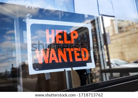 Reflection of a silhouette of a man looking at a help wanted sign in a business window, economy concept, shallow focus on middle of sign