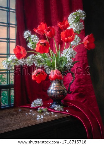 Still life with bouquet of red tulips and blooming tree branch