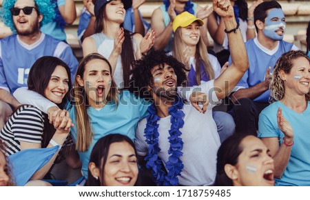 Argentinian spectators in stadium cheering their national football team. People from Argentina in fan zone cheering for their soccer team. Royalty-Free Stock Photo #1718759485
