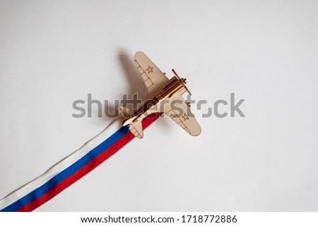 plane with the Russian flag. The background for the cards to win the Day. Background for congratulations on may 9. Wooden plane with a ribbon of the colors of the Russian flag. Children's toy plane fo Royalty-Free Stock Photo #1718772886