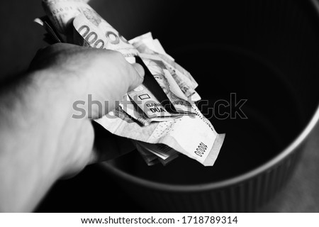 A man throwing various currencies (money) into a bin. Global economic crisis concept image. 