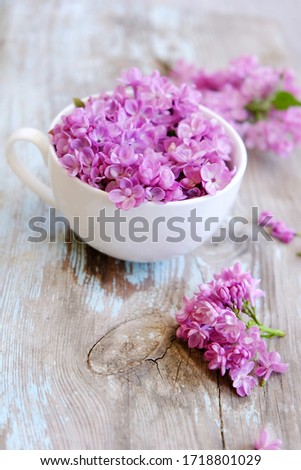 Cup of tea with lilac flowers on wooden background. Spring time. Vase with lilac. Copy space for text. The concept of holidays and good morning wishes.