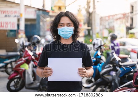 Asian man is wearing mask holding empty sign board to support campaign during covid19 or corona virus spread