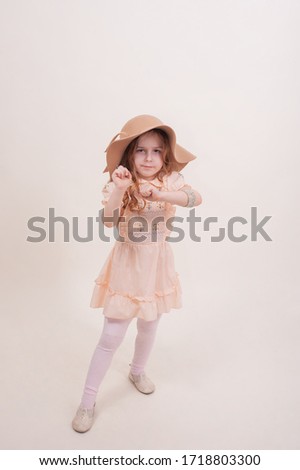little cute girl in a dress. Little girl in a hat and dress in the studio.The emotions of a child.