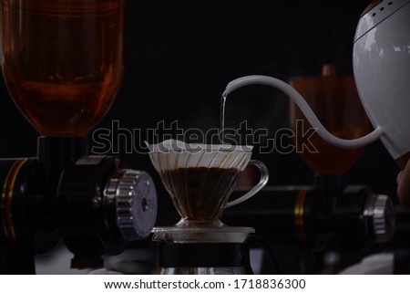 
a man pours hot water from a kettle into a coffee dripper. Royalty-Free Stock Photo #1718836300