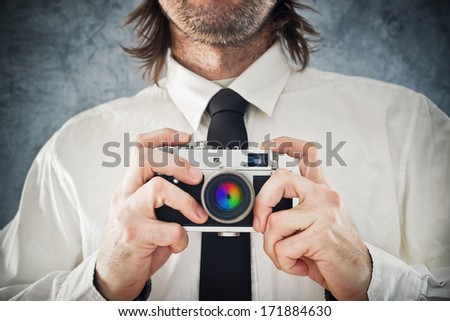Businessman taking picture with retro style photo camera