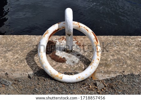 Large White Painted Iron Mooring Ring on Concrete Edge of Industrial Canal