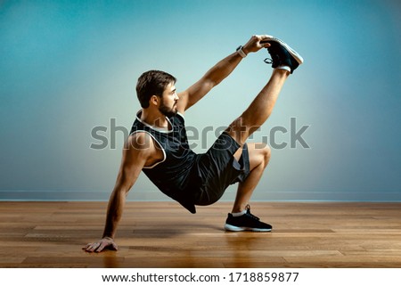 A man does functional exercises in the gym on a gray background. Fitness concept, sports body, body positive, copy space Royalty-Free Stock Photo #1718859877