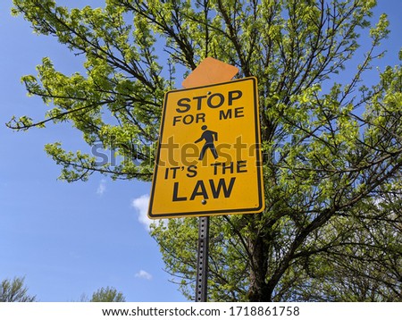 Low angle view of a Stop For Me It's The Law yellow street sign on a bright, sunny day