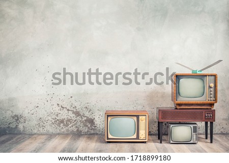 Retro cathode ray tube (CRT) monochrome television sets and classic wooden TV stand with outdated amplifier front concrete wall background. Broadcasting, news concept. Vintage old style filtered photo Royalty-Free Stock Photo #1718899180