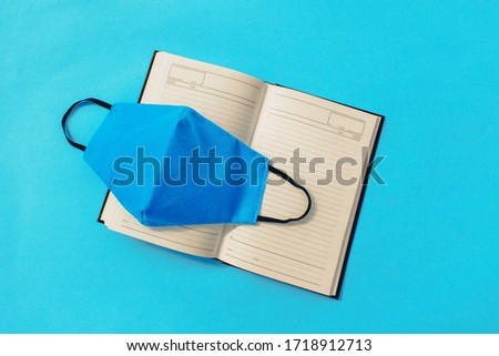 Diary and medical mask on a colored background. Healthcare concept.