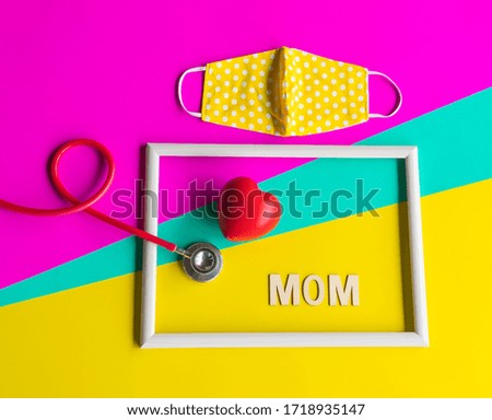 Creative  happy  mother  day  setting  with  blank  wooden  picture  frame,stethoscope,red  heart  shape  and    cloth  mask  on  pastel  paper  color  background