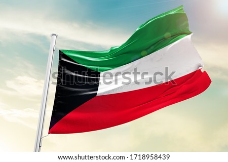 Kuwait national flag cloth fabric waving on the sky with beautiful sky - Image Royalty-Free Stock Photo #1718958439