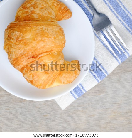 Croissant on white plate on wooden rustic background, Balanced diet.
