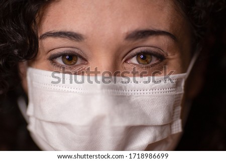 Woman smiles with medical mask on amidst the coronavirus pandemic, 2020.  Closeup portrait.
