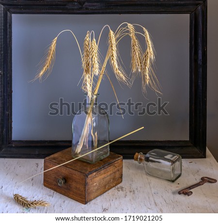 Still life with a bouquet of ears of wheat, a wooden box, a picture frame and a key. Vintage. Interior.