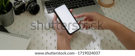 Cropped shot of male entrepreneur using blank screen smartphone to find information for his work while sitting at worktable