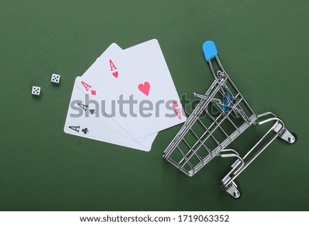 Shopping trolley with four aces and dice on a green background. Top view