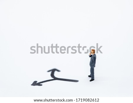 Businessman miniature people figure thinking and looking to direction left or tight arrow on white background with copy space using for business,marketing and financial concept.