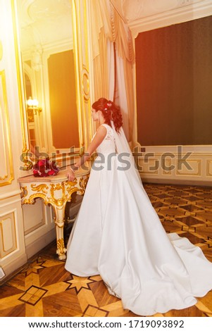 Beautiful bride looking in the mirror indoors, photo in the castle.