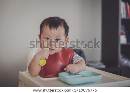 Happy infant baby boy spoon eats itself. he is 10 months old. Royalty-Free Stock Photo #1719096775