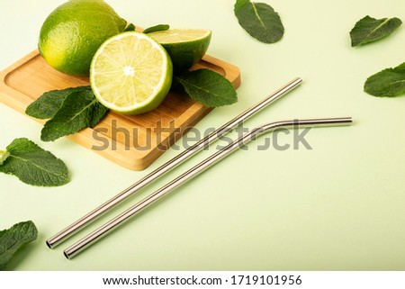Reusable metal straws on a pastel background. Fresh lime and mint fruits lie on a wooden stand.  Royalty-Free Stock Photo #1719101956