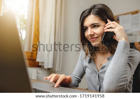 woman talking on the phone while working on computer in desk office. Searching on internet Royalty-Free Stock Photo #1719141958
