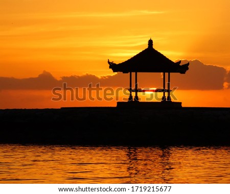 A Gazebo Silhouette during beautiful orange and warm Sunrise at Sanur Beach Bali             