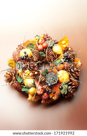 Halloween wreath with pinecones and pumpkins on brown background.