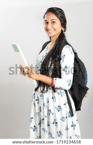 Indian college girl holding books and backpack