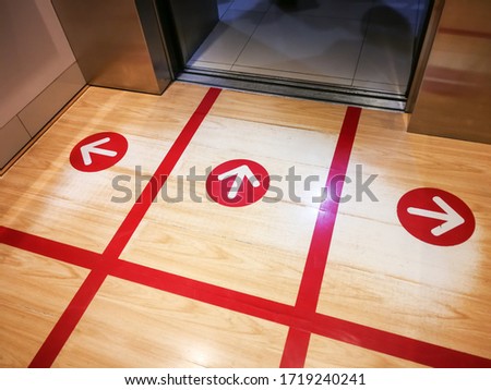 Red tape on the elevator or lift floor with arrow sign for direction of standing position to limit or control number of people entry into the lift ,Social distancing in COVID-19 or coronavirus crisis