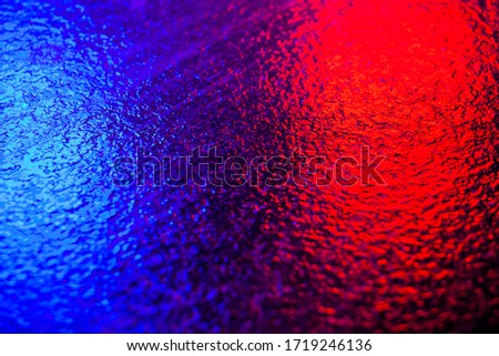 Abstract photo reflection of light on a wet surface. Blue-red neon light on a textured wet surface. Reflection of lights on the pavement