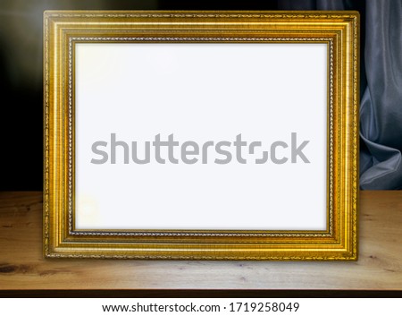 Wooden table, gold vintage frame, dark background with darck drapery. Free space for your design and home interior, mock up