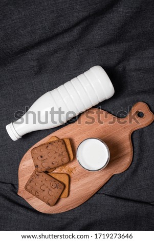 Cookies on a wooden board. Milk in a bottle and in a transparent glass.
Photo on a dark background
