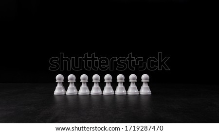 White Chess pawn in a raw on black background.