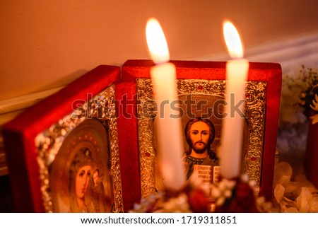 Orthodox icon stands on the table and candles are burning