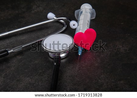 Red heart with stethoscope and syringe injection on table, world health day and healthcare concept.