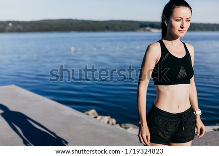Photo of beautiful young sports woman running outdoors listening music.