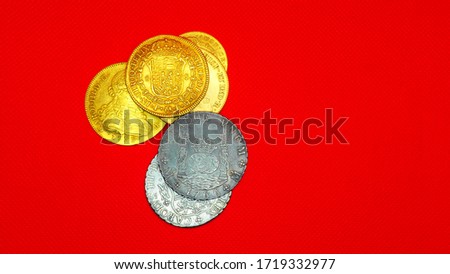 Gold and silver coins on red background mat. Numismatics, old Spanish coins.