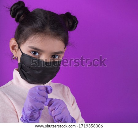 Little cute girl with black mask on purple background. Stay home. Stop covid-19. Dispasoble mask. Virus protection equipment. Quarantine. Girl plays a doctor. education and occupation concept